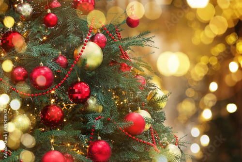 Christmas tree decorated with red and golden festive balls against blurred background  bokeh effect. Space for text
