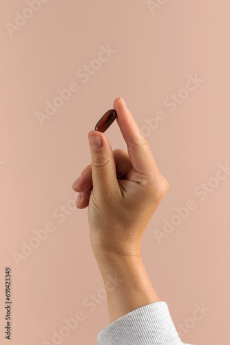 A woman's hand holds a pill with a medicinal supplement . Healthcare, food additives and medicines.