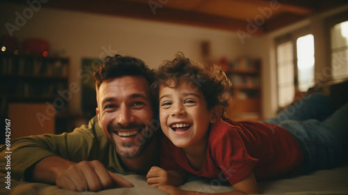 Cheerful father and son having fun lying on floor and smiling, parents and children being friends photo