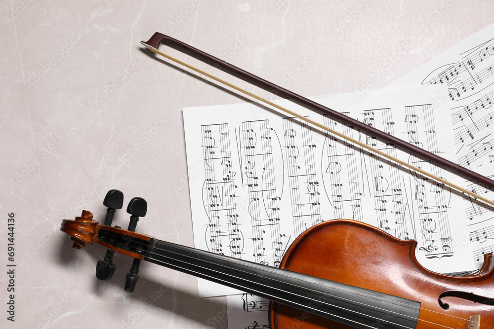 Naklejka premium Violin, bow and music sheets on grey marble table, top view