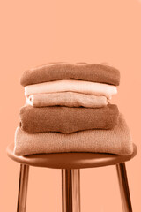 Crédence de cuisine Pantone 2024 Peach Fuzz Warm knitwear in a pile on a chair on a peach background. Second hand, wardrobe sorting, cross-dressing, economic crisis, money saving, waste reduction, compassion, connection.  © 7707601