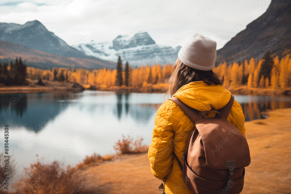 a woman in a yellow jacket and hat looking at a lake