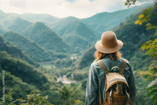a woman with a hat and backpack looking at a valley
