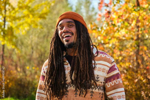 African American young man with dreadlocks laughing and looking at camera in a sunny day of autumn. photo
