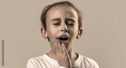 Child suffer from toothache. Anti toothache remedy. Toothache painkiller. Dental disease. Toothache in children, unhealthy little boy touching cheek, feeling severe toothache, oral health problems photo