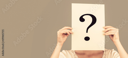 Woman holding interrogation symbol in front of her face. Female incognita. Girl question, anonymous, incognita. Girl holding paper question mark. Anonymous, woman question, incognita. Anonymous woman