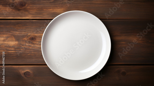 White plate with cutlery at dark wooden table. Top view
