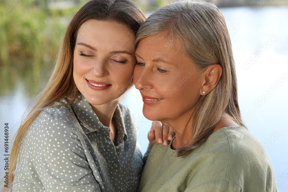 Family portrait of happy mother and daughter spending time together outdoors, closeup Family portrait of happy mother and daughter spending time together outdoors, closeup