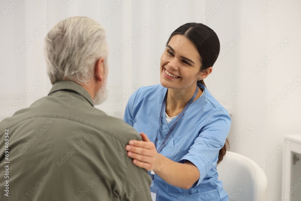Smiling nurse supporting elderly patient in hospital Smiling nurse supporting elderly patient in hospital