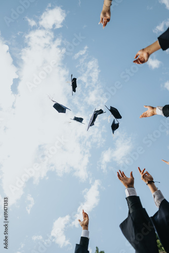 A group of happy students celebrating graduation in a park, throwing caps in the air, symbolizing their success and teamwork. They cherish university memories and create beautiful milestones.