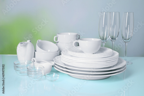 Set of clean dishes and glasses on light blue table