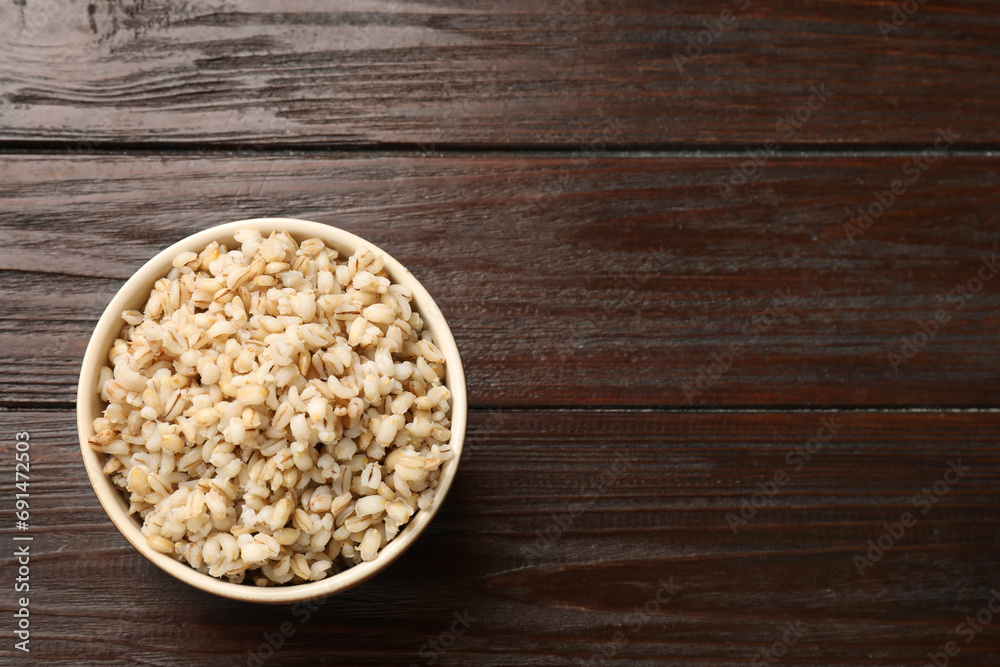 Delicious pearl barley in bowl on wooden table, top view. Space for text Delicious pearl barley in bowl on wooden table, top view. Space for text