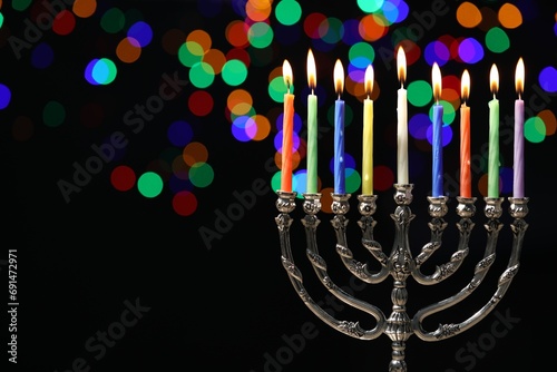 Hanukkah celebration. Menorah with burning candles against dark background with blurred lights, space for text