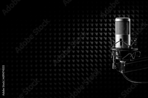 Professional microphone on the black acoustical wall panel. Recording studio, copy space.