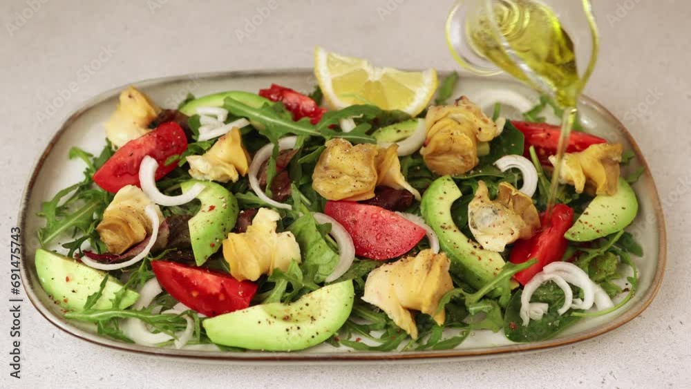 Warm salad with rapan (snails), tomatoes, avocado, onions, leafy vegetables, lemon and olive oil. Traditional salad with seafood. A woman pours oil on a salad. Close-up, selective focus. Warm salad with rapan (snails), tomatoes, avocado, onions, leafy vegetables, lemon and olive oil. Traditional salad with seafood. A woman pours oil on a salad. Close-up, selective focus.