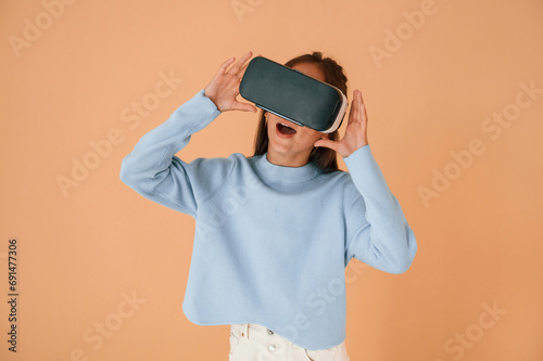 Shocked by virtual reality experience, in glasses. Cute young girl is in the studio against background
