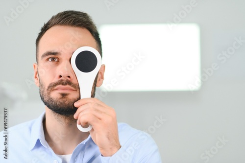 Portrait, vision and spoon with a man patient at the optometrist for an eye exam testing his depth perception photo