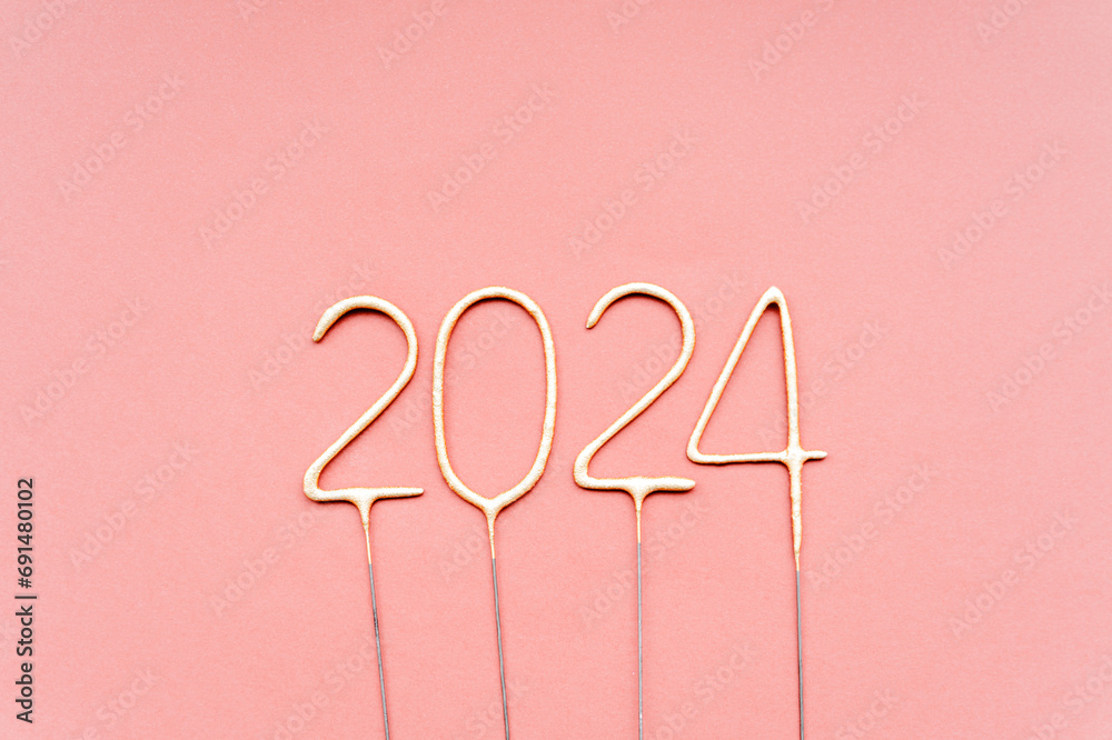 Golden sparklers in the form of the numbers 2024 on a pink background