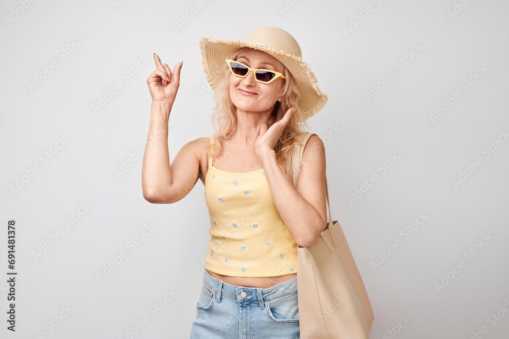 Beautiful mature woman 50 years old pointing finger aside, demonstrating empty space for product or text isolated on white studio background Beautiful mature woman 50 years old pointing finger aside, demonstrating empty space for product or text isolated on white studio background