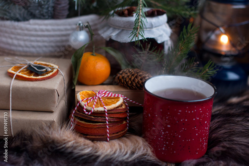 hot tea in a steamed mug, dry orange slices. Cold winter in the village, Cherry jam on the background of a burning lantern and natural fox fur. photo