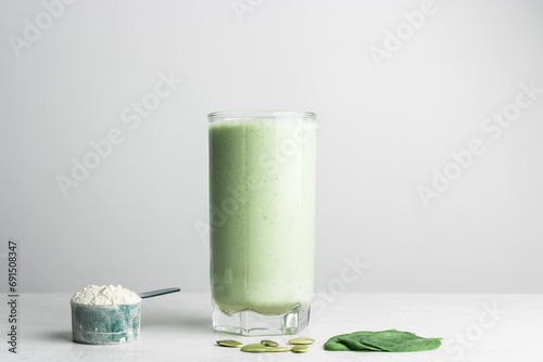 Green detox smoothie, blended vegetarian drink in a glass from protein powder, spinach and seeds on a table, healthy eating concept photo