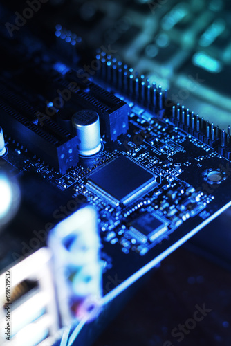 closeup of computer mainboard, electronic circuit board, electrical components in pc. dark blue lighting
