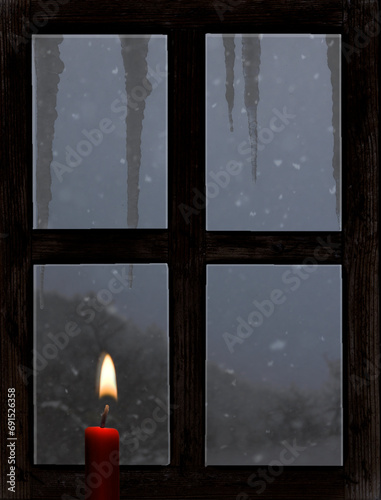 Blick durch ein altes Holzfenster mit Kerze im Winter