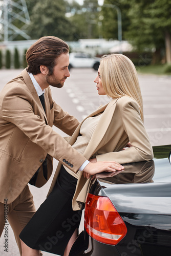 elegant man in formal wear looking at sensual blonde businesswoman near car on street, attraction © LIGHTFIELD STUDIOS