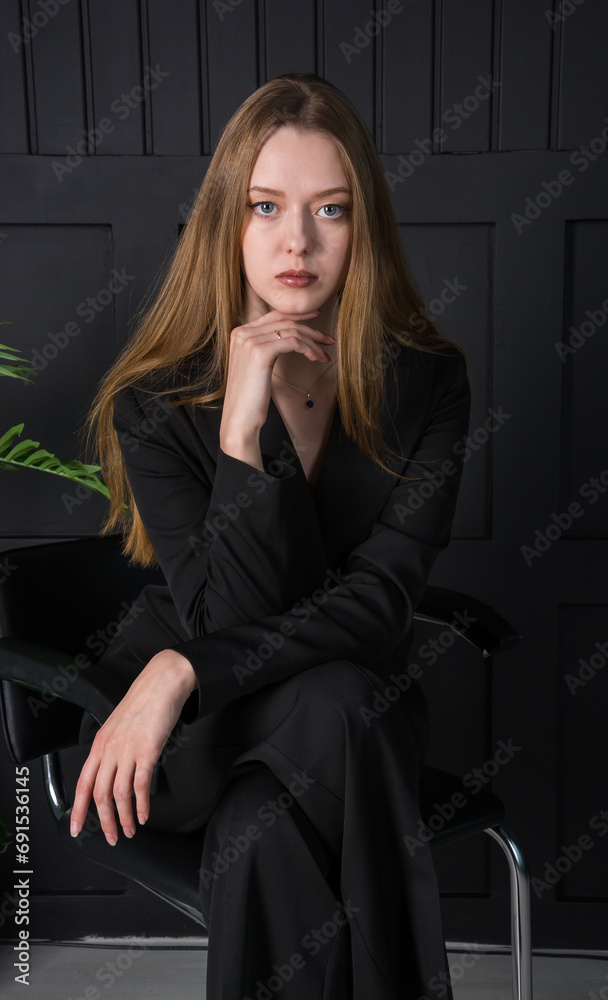 Young beautiful woman, fashion model, in a black suit in the studio