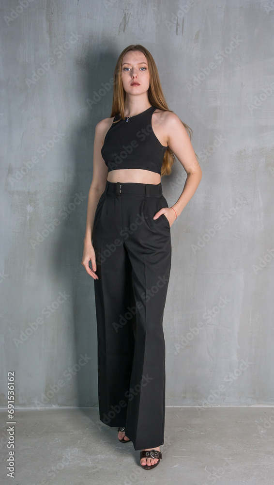 Young beautiful woman, fashion model, in a black suit in the studio