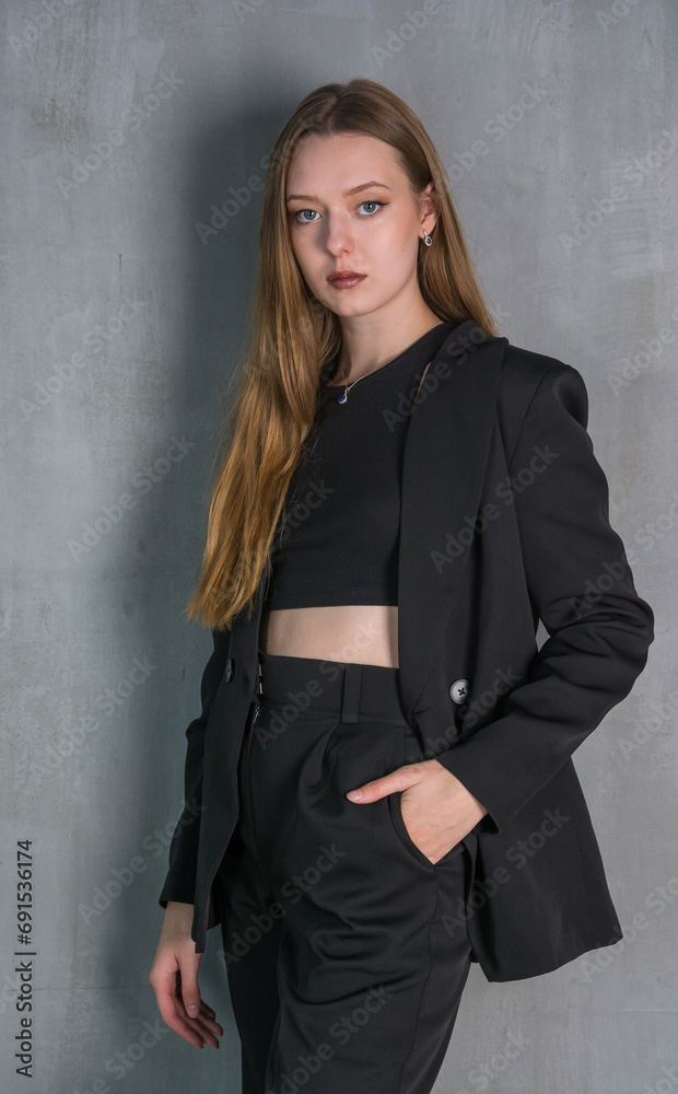 Young beautiful woman, fashion model, in a black suit in the studio