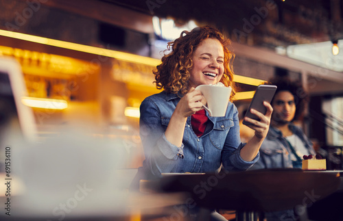 Laughing young woman using smartphone in cafe photo
