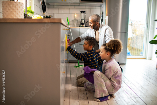 Father and children cleaning home kitchen photo