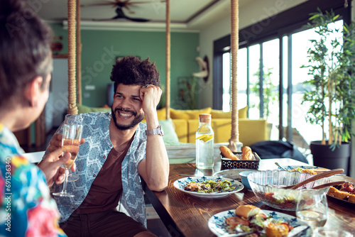Smiling young man drinking champagne with woman at lunch table photo