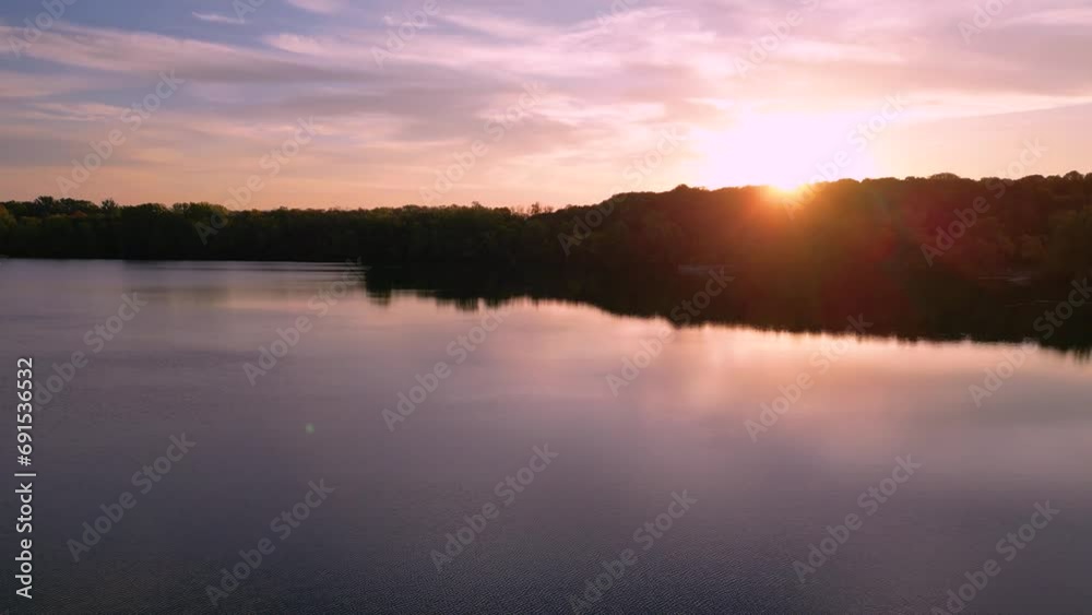 Stunning pink sunrise over the clear lake. Trees, sky and clouds are reflecting in the lake Stunning pink sunrise over the clear lake. Trees, sky and clouds are reflecting in the lake