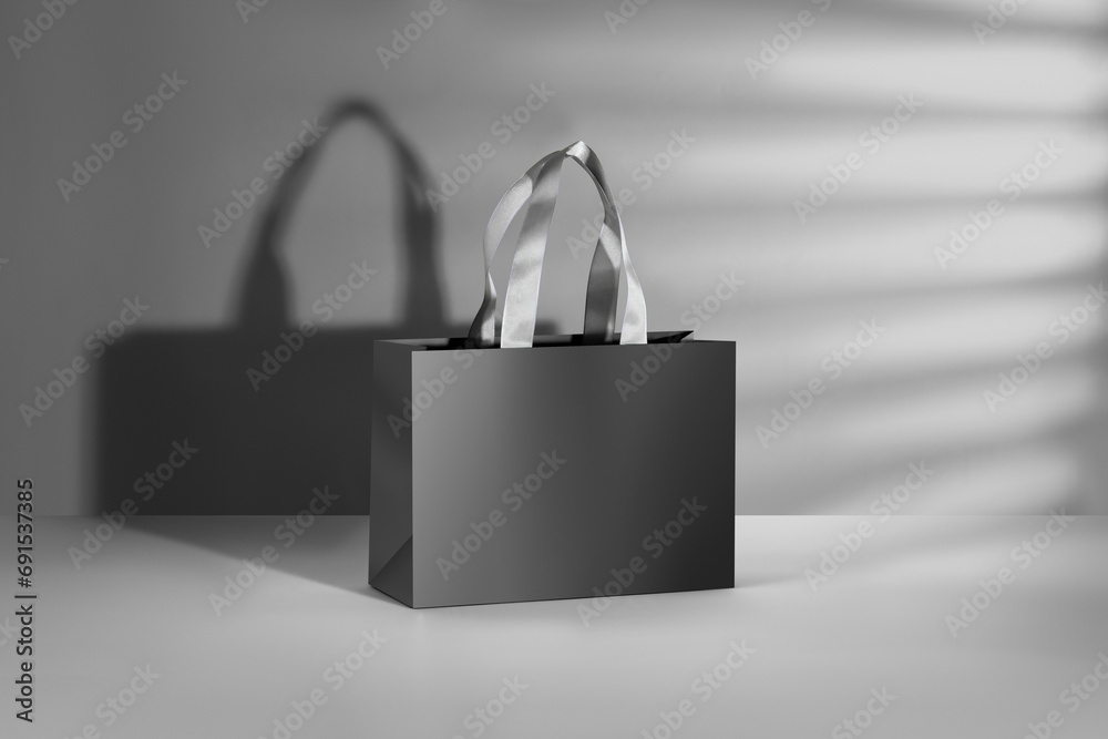 Black paper glossy shopping bag mockup with white handles. - obrazy, fototapety, plakaty 