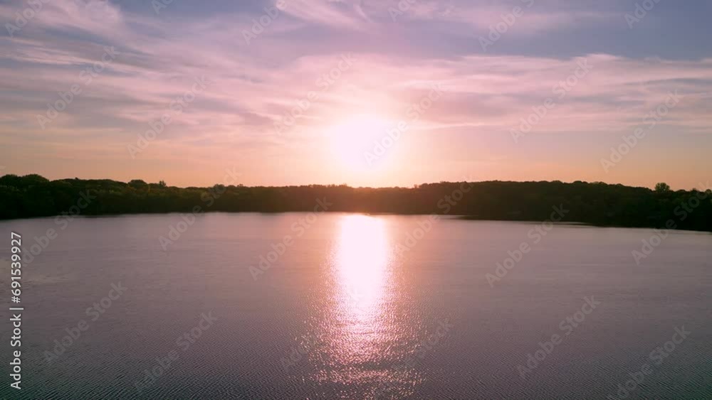 Stunning pink sunrise over the clear lake. Trees, sky and clouds are reflecting in the lake Stunning pink sunrise over the clear lake. Trees, sky and clouds are reflecting in the lake