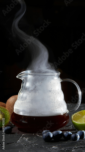 Hot coffee in a glass teapot on a black stone table with fruit. © Лев Малевич