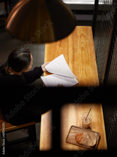 A girl in a cafe looks through documents. © Лев Малевич