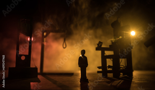 Execution concept. Death penalty electric chair miniature in selective focus inside old prison. Old prison bars cell lock. Creative artwork decoration. Electric chair scale model in the dark