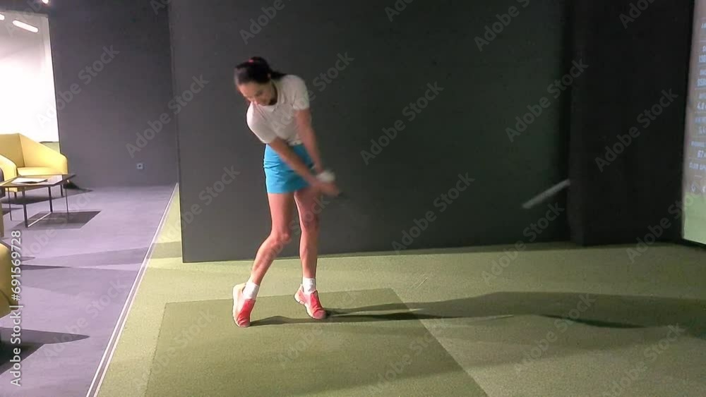 Professional female golfer holding club playing golf indoors on golf simulator Professional female golfer holding club playing golf indoors on golf simulator