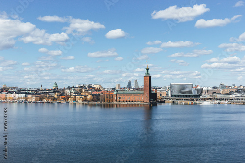 panoramic view of rooftops and view of the town hall tower with many colorful houses in stockholm and water channels huge boat and cloudy sky © Radu