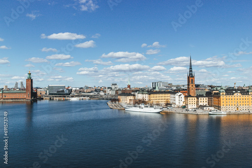 panoramic view of rooftops and view of the town hall tower with many colorful houses in stockholm and water channels huge boat and cloudy sky