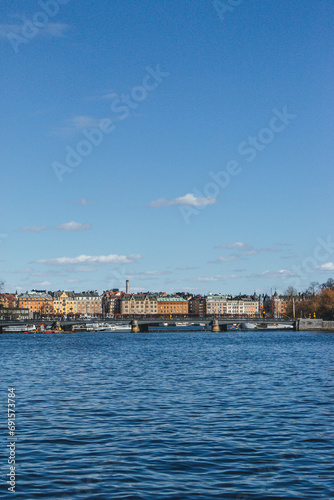 panoramic view of rooftops and view of the town hall tower with many colorful houses in stockholm and water channels huge boat and cloudy sky © Radu