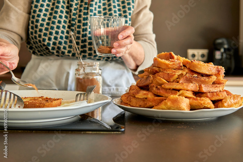 Unrecognizable senior woman spreading panela sugar on the bread for torrijas recipe