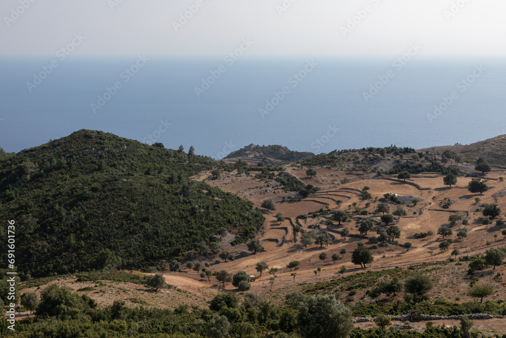 Mediterranean rocky landscape. Mountains in the distance. Multilevel Yellow grass terraces with stone fences. Turkish countryside.