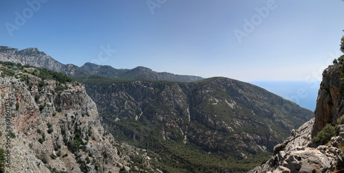A wide mountain gorge on the shores of the Mediterranean Sea. There are steep cliffs all around. In the middle there is a deep abyss without a bottom.
