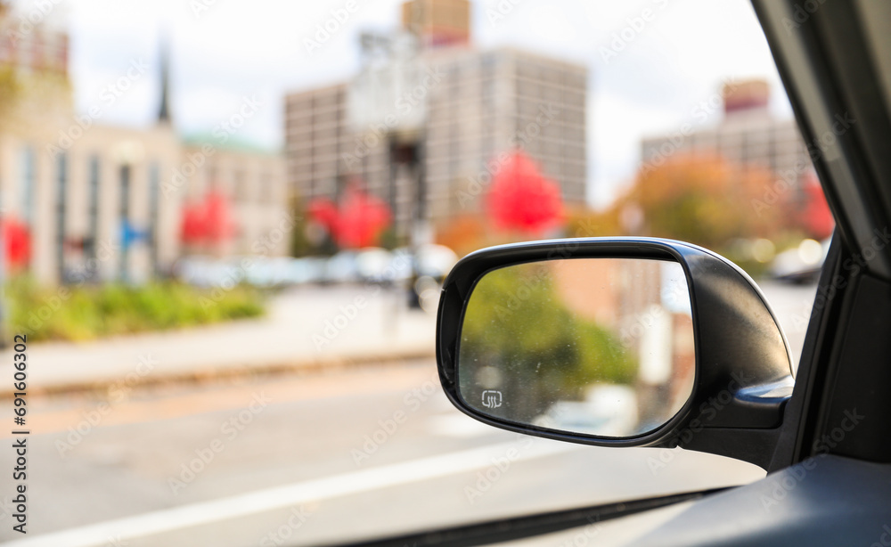 car mirror reflecting cityscape, symbolizing travel, reflection, urban lifestyle, and exploration. Blurred background