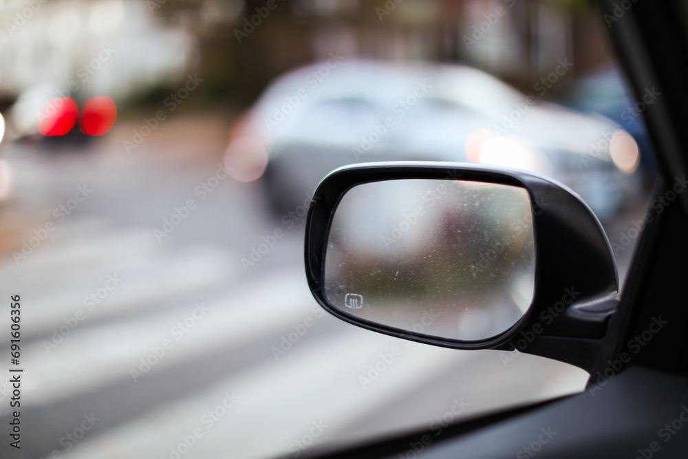 car mirror reflecting cityscape, symbolizing travel, reflection, urban lifestyle, and exploration. Blurred background