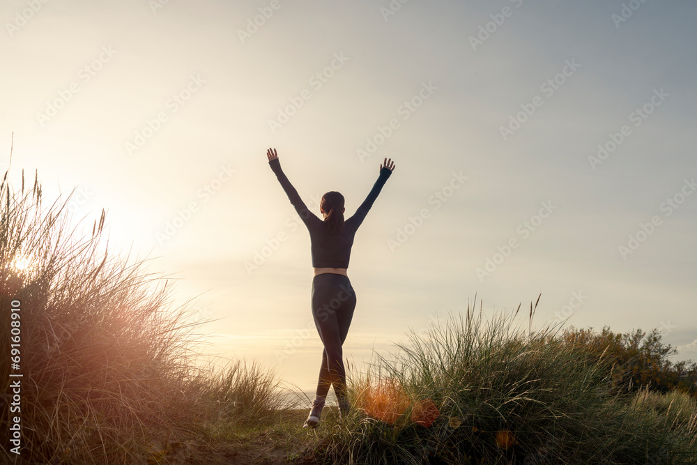 sporty woman with arms up celebrating goals after sport exercising and working out outdoors after a morning run sporty woman with arms up celebrating goals after sport exercising and working out outdoors after a morning run
